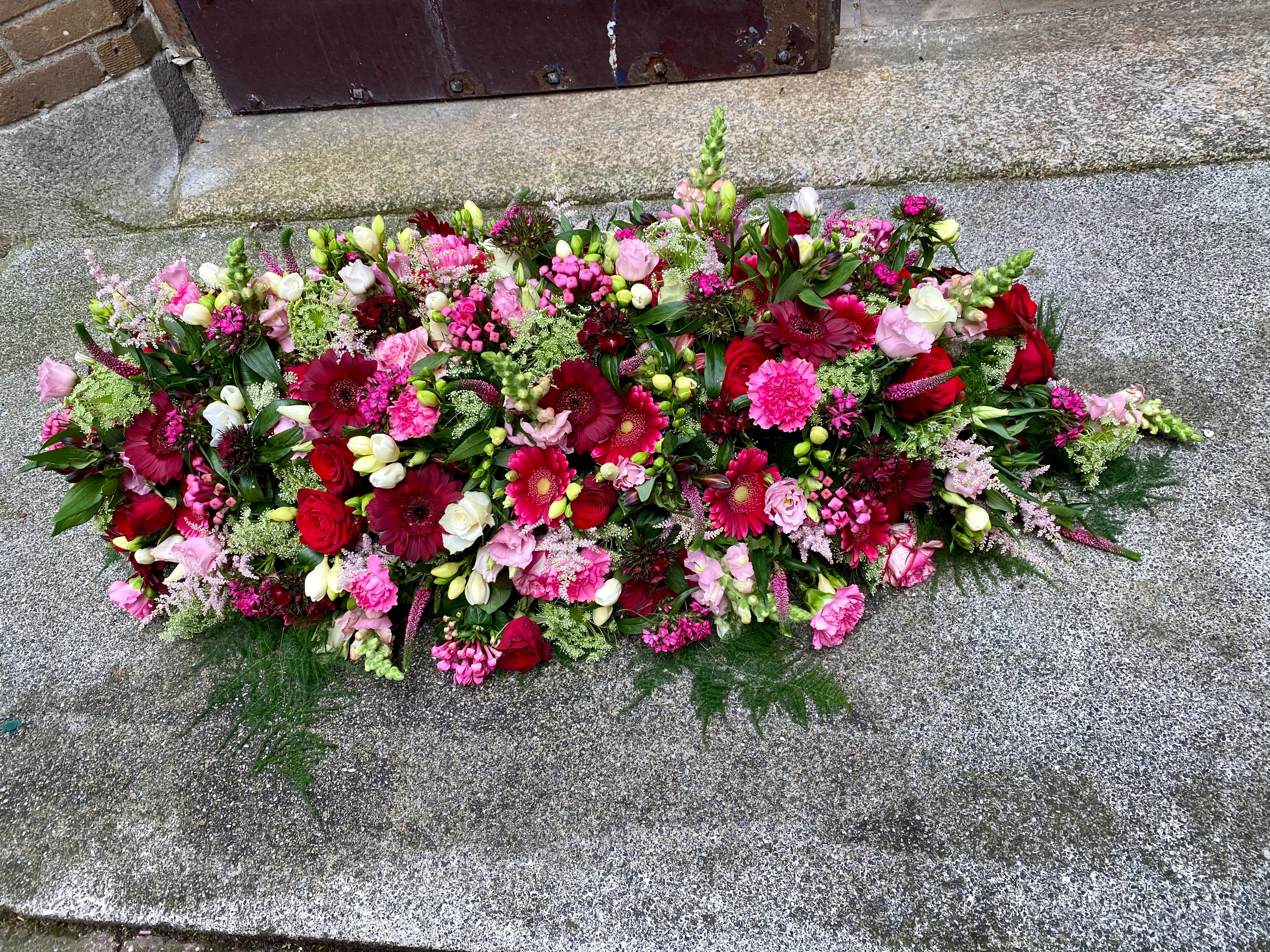 Langwerpig bloemstuk in rood en roze